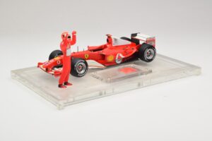 Ferrari F2004 #1 M. Schumacher F1 World Champion 2004 Z Dirkalnim Kombinezonom Hot Wheels 1:18 B66221 Kovina